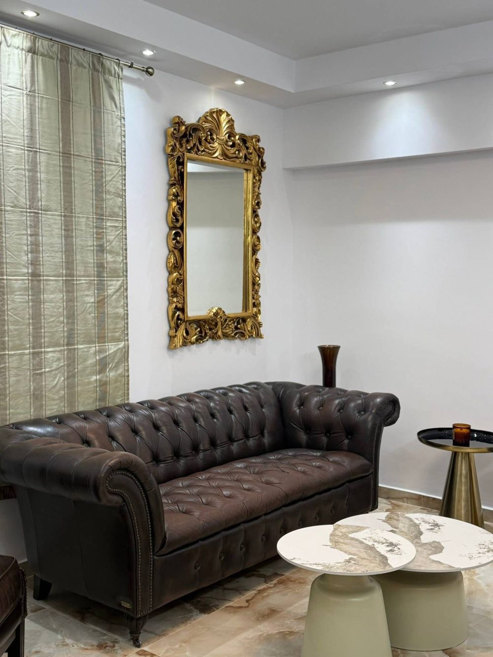 Χώρος αναμονής με δερμάτινο καναπέ Chesterfield και επιχρυσωμένο σκαλιστό καθρέφτη.
